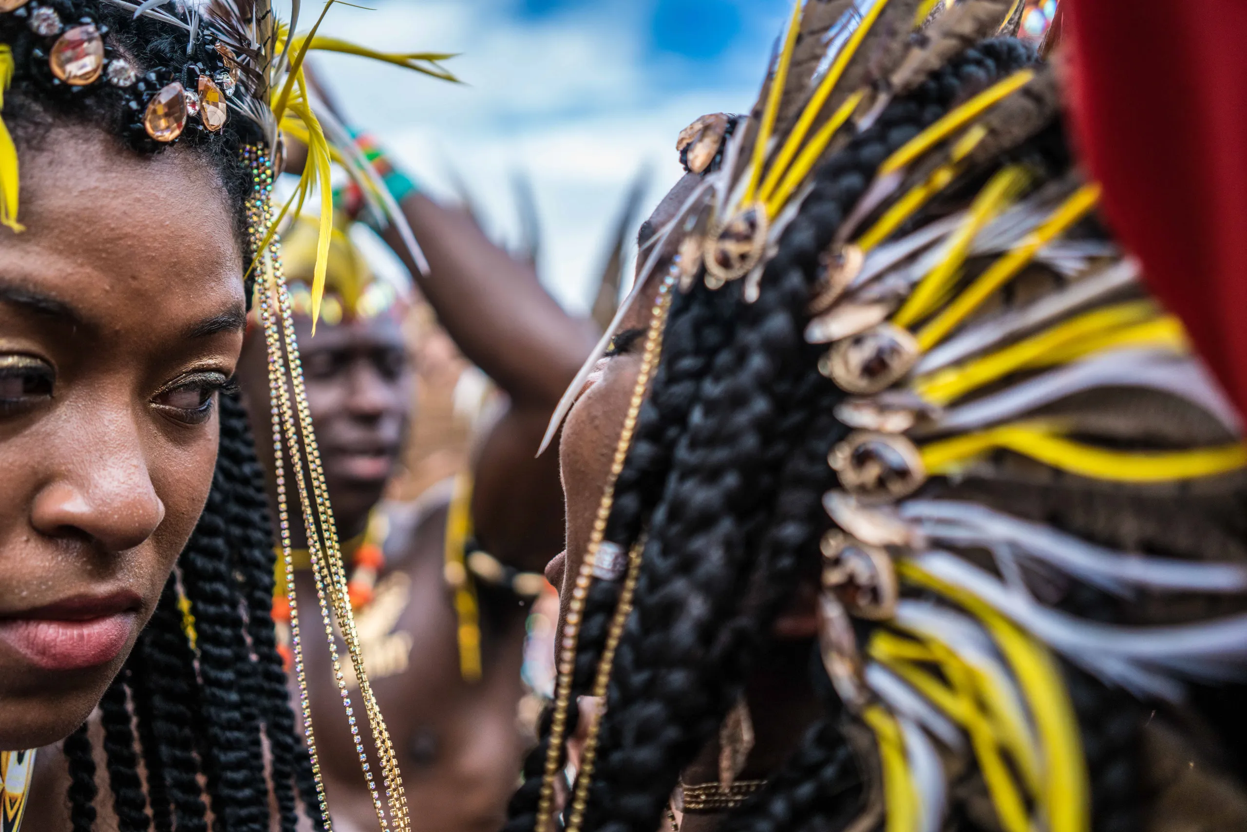 A masquerader with braids and a feathered headdress