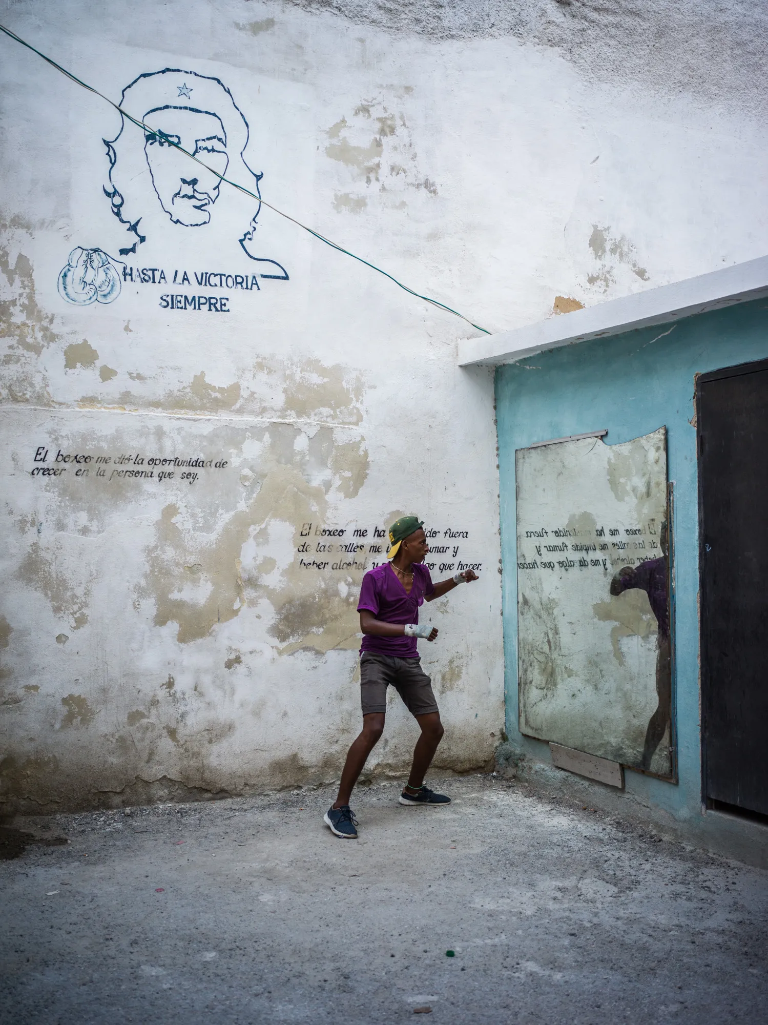 A boy shadowboxing against a painted wall