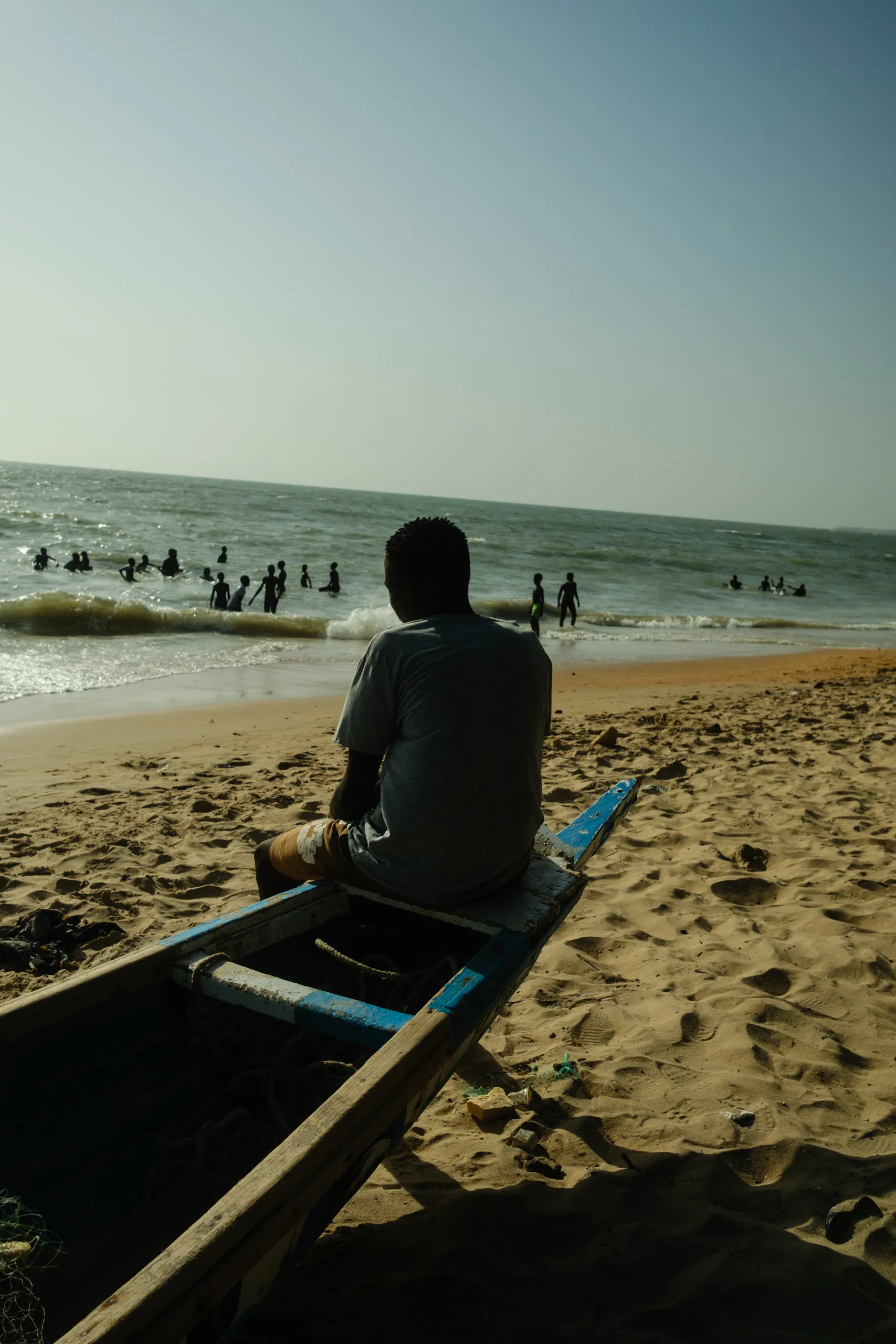 A boy sitting in a fishing boat on the shore
